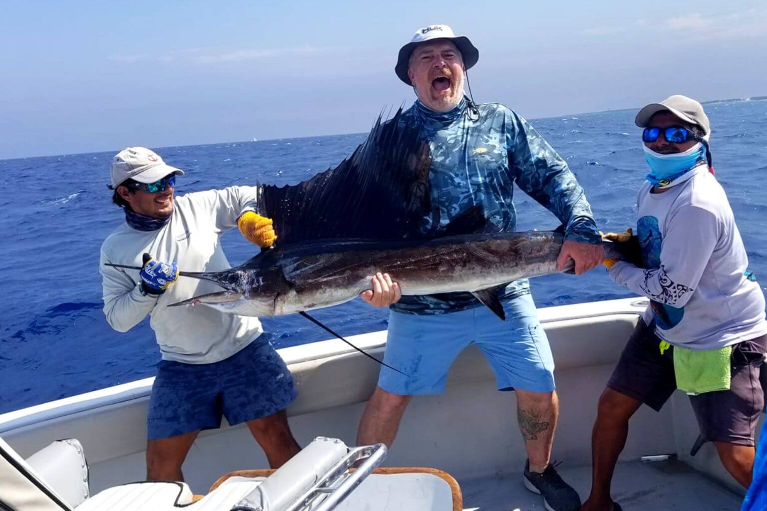 Man holding a sailfish caught on a fishing charter from Puerto Aventuras